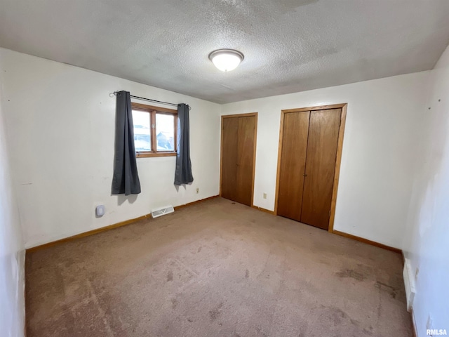 915 S 5th St, Clinton, IA 52732 - unfurnished bedroom featuring two closets, light colored carpet, and a textured ceiling