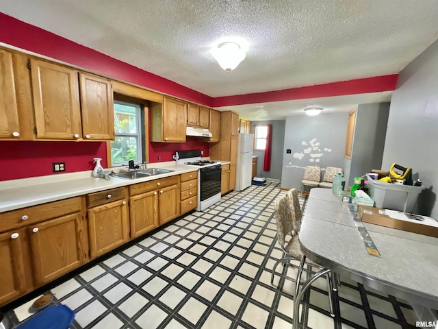 915 S 5th St, Clinton, IA 52732 - kitchen featuring white appliances, under cabinet range hood, a textured ceiling, light countertops, and brown cabinetry