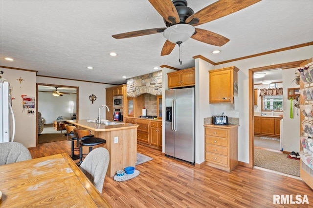 524 6th St, Andover, IL 61233 - kitchen featuring appliances with stainless steel finishes, ceiling fan, crown molding, light wood-style flooring, and a center island with sink