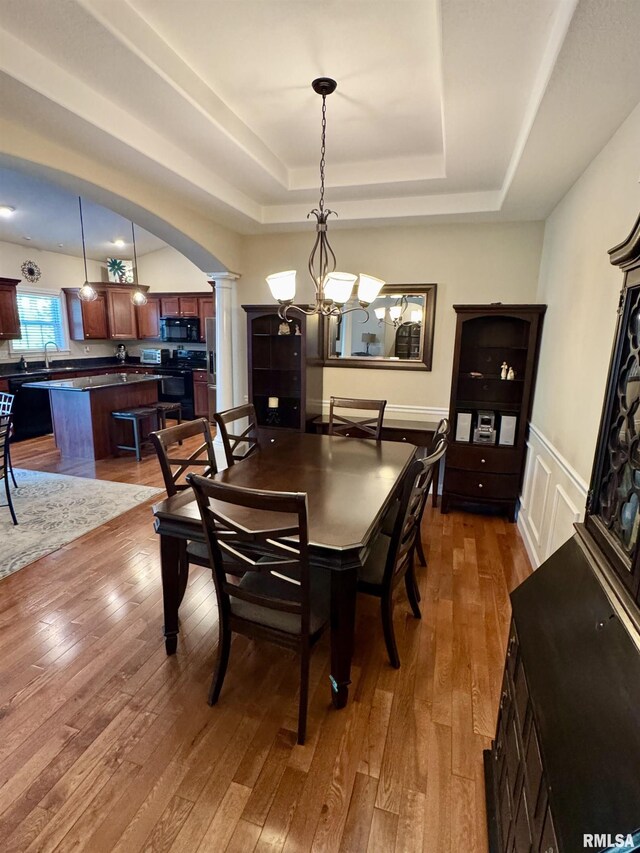 310 Westminster Rd, Germantown Hills, IL 61548 - dining room with ornate columns, a tray ceiling, hardwood / wood-style floors, a chandelier, and arched walkways