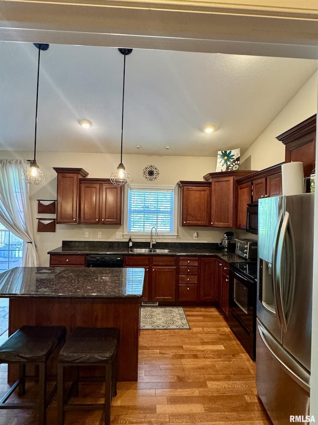 310 Westminster Rd, Germantown Hills, IL 61548 - kitchen with black appliances, light wood-type flooring, a center island, decorative light fixtures, and a breakfast bar