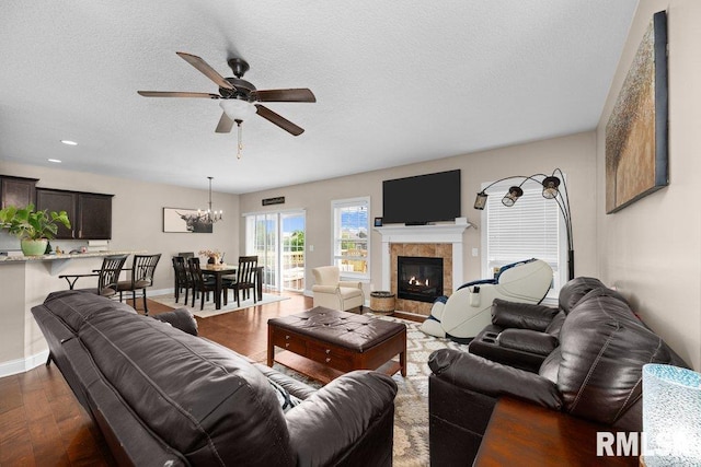 67 Cobblestone Ln, Le Claire, IA 52753 - living area with ceiling fan, a textured ceiling, dark wood-style floors, a tiled fireplace, and a chandelier