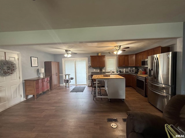 172 E Meadow Ln, Walcott, IA 52773 - kitchen with stainless steel appliances, ceiling fan, a breakfast bar area, and dark wood finished floors
