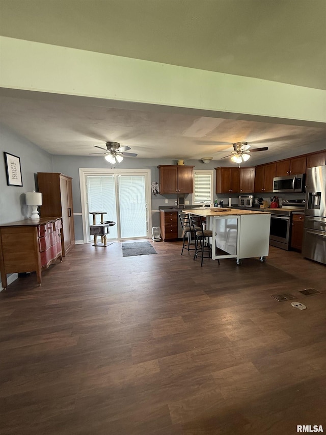172 E Meadow Ln, Walcott, IA 52773 - kitchen featuring stainless steel appliances, a ceiling fan, a breakfast bar, and dark wood finished floors