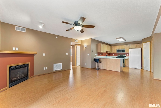 3215 S 16th Ave Unit 201, Eldridge, IA 52748 - unfurnished living room featuring a glass covered fireplace, ceiling fan, and light wood-style flooring