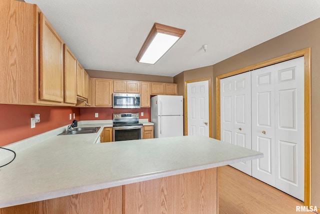 3215 S 16th Ave Unit 201, Eldridge, IA 52748 - kitchen featuring appliances with stainless steel finishes, light countertops, a peninsula, light wood-type flooring, and light brown cabinets