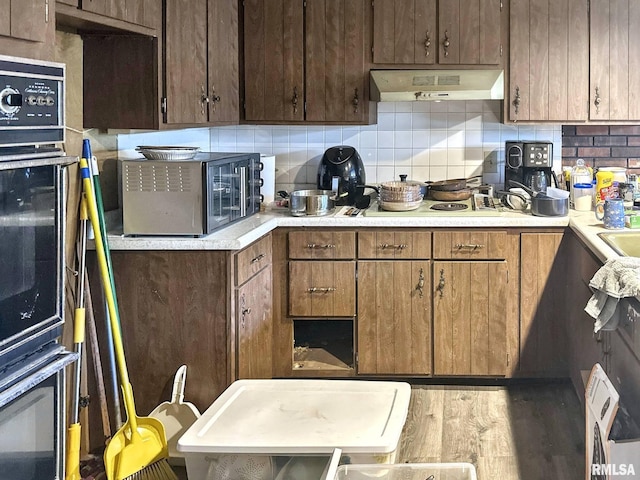 900 E 4th St, West Frankfort, IL 62896 - kitchen featuring custom range hood, decorative backsplash, light countertops, and wood finished floors