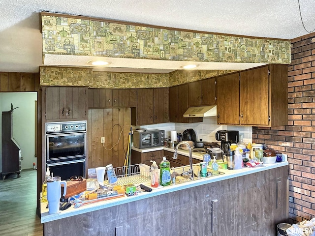 900 E 4th St, West Frankfort, IL 62896 - kitchen featuring range hood, a textured ceiling, light countertops, wood finished floors, and a peninsula