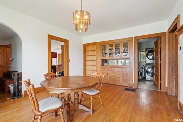 829 Union Ave, Lowden, IA 52255 - dining space with stacked washer and clothes dryer, arched walkways, light wood-type flooring, and a chandelier