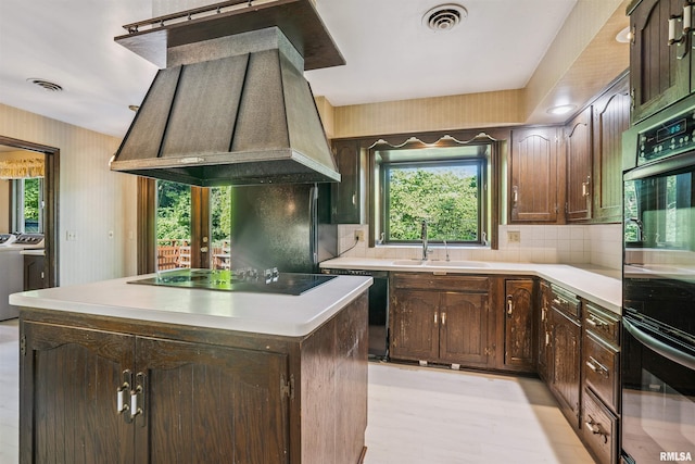2351 5th St, East Moline, IL 61244 - kitchen featuring washer and dryer, black appliances, custom range hood, a center island, and light countertops