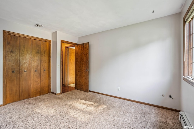 2351 5th St, East Moline, IL 61244 - unfurnished bedroom with a baseboard heating unit, a closet, carpet floors, and multiple windows
