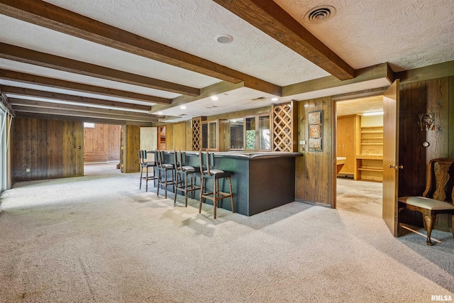 2351 5th St, East Moline, IL 61244 - indoor dry bar featuring wooden walls, beamed ceiling, a textured ceiling, light colored carpet, and plenty of natural light