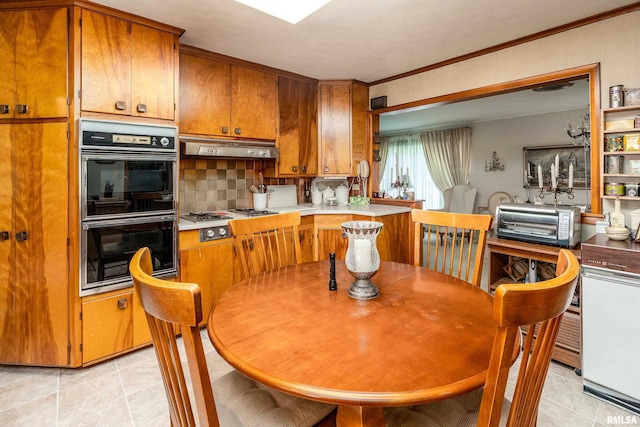 613 S Locust, West Frankfort, IL 62896 - kitchen with under cabinet range hood, brown cabinets, decorative backsplash, light tile patterned floors, and light countertops