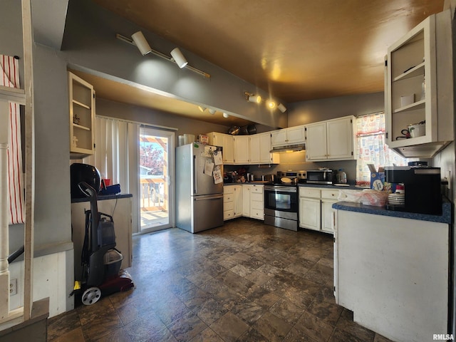 3217 18th Ave, Rock Island, IL 61201 - kitchen featuring appliances with stainless steel finishes, dark countertops, under cabinet range hood, white cabinets, and vaulted ceiling