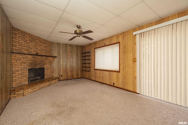 2518 13th St, Rock Island, IL 61201 - unfurnished living room with ceiling fan, wooden walls, carpet flooring, a paneled ceiling, and a fireplace