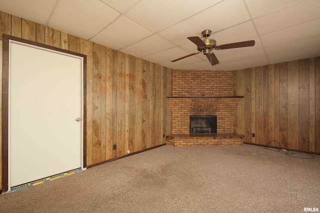 2518 13th St, Rock Island, IL 61201 - unfurnished living room with a paneled ceiling, wood walls, a ceiling fan, carpet, and a brick fireplace