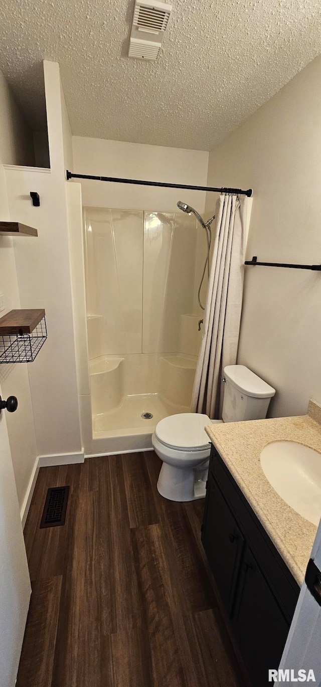 2337 Cameron Dr, Clinton, IA 52732 - full bathroom with curtained shower, wood finished floors, vanity, and a textured ceiling