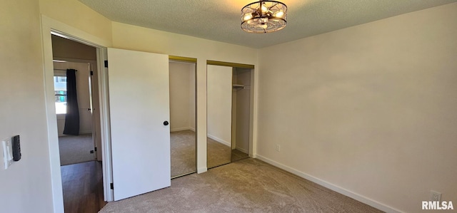 2337 Cameron Dr, Clinton, IA 52732 - unfurnished bedroom with carpet flooring, multiple closets, a chandelier, and a textured ceiling