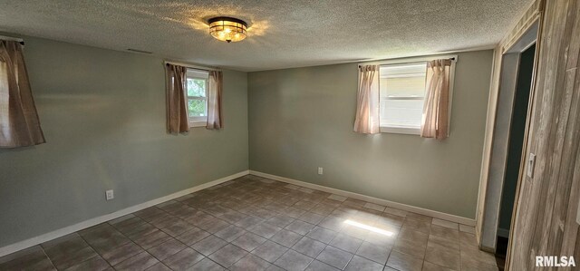 2337 Cameron Dr, Clinton, IA 52732 - spare room featuring a textured ceiling and dark tile patterned floors