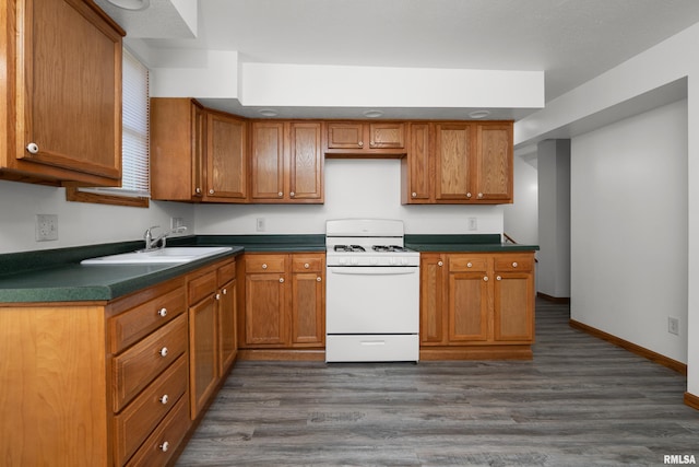 222 6th St, Buffalo, IA 52728 - kitchen featuring white gas range, dark countertops, and brown cabinetry