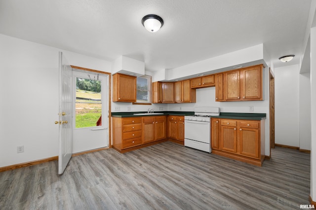 222 6th St, Buffalo, IA 52728 - kitchen featuring white range with gas cooktop, wood finished floors, dark countertops, and brown cabinets
