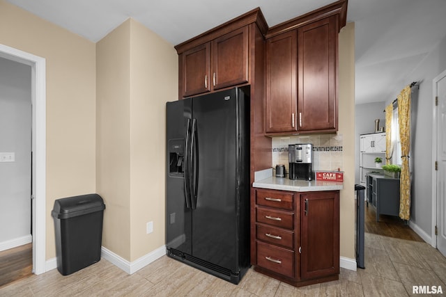 4040 27th Ave, Rock Island, IL 61201 - kitchen featuring black fridge with ice dispenser, light countertops, backsplash, and light wood finished floors