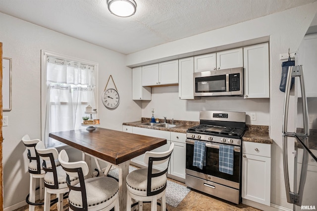 24 Berkshire Dr, Rock Island, IL 61201 - kitchen featuring appliances with stainless steel finishes, dark countertops, white cabinets, and a textured ceiling