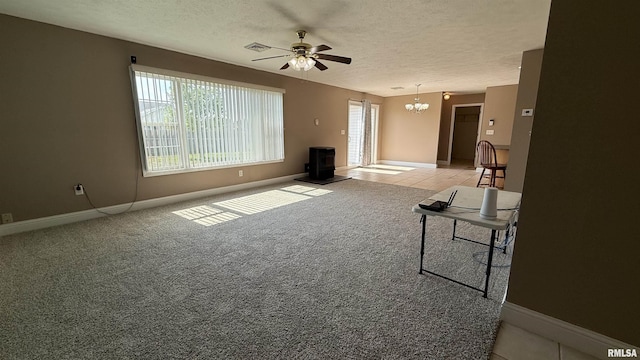11279 Nora Ln, Carterville, IL 62918 - unfurnished living room featuring a wood stove, a textured ceiling, a ceiling fan, a chandelier, and light colored carpet