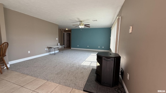 11279 Nora Ln, Carterville, IL 62918 - unfurnished living room with a wood stove, a ceiling fan, light colored carpet, light tile patterned floors, and a textured ceiling