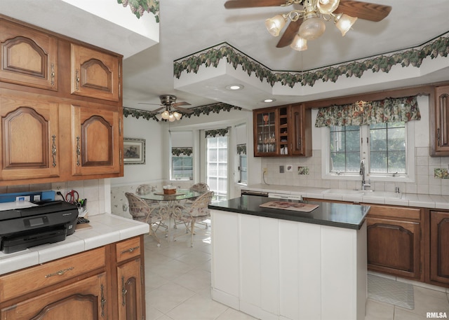 8527 W 17th St, Rock Island, IL 61201 - kitchen featuring ceiling fan, light tile patterned floors, decorative backsplash, brown cabinetry, and a kitchen island