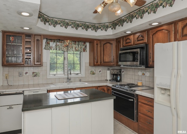 8527 W 17th St, Rock Island, IL 61201 - kitchen with appliances with stainless steel finishes, backsplash, a ceiling fan, glass insert cabinets, and tile countertops
