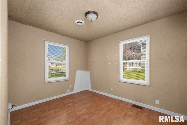 2043 30th St, Rock Island, IL 61201 - empty room featuring healthy amount of natural light, wood finished floors, and a textured ceiling