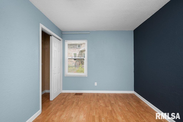 2043 30th St, Rock Island, IL 61201 - unfurnished bedroom featuring light wood finished floors, a closet, and a textured ceiling