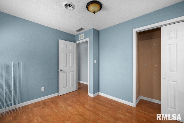2043 30th St, Rock Island, IL 61201 - unfurnished bedroom with a heating unit, wood finished floors, a textured ceiling, and a textured wall