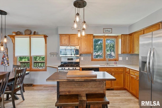 129 Glenview Dr, Sherrard, IL 61281 - kitchen with appliances with stainless steel finishes, backsplash, light wood-type flooring, and hanging light fixtures