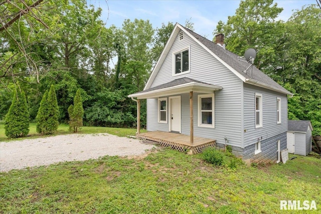 619 51st St, Moline, IL 61265 - view of front of property featuring a shingled roof, a chimney, a front lawn, a shed, and covered porch