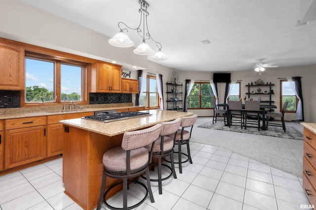 12828 25th Street Ct, Milan, IL 61264 - kitchen featuring stainless steel gas stovetop, a kitchen island, light colored carpet, and tasteful backsplash