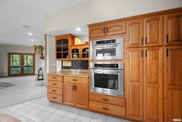 12828 25th Street Ct, Milan, IL 61264 - kitchen with light colored carpet, glass insert cabinets, brown cabinets, light stone counters, and recessed lighting