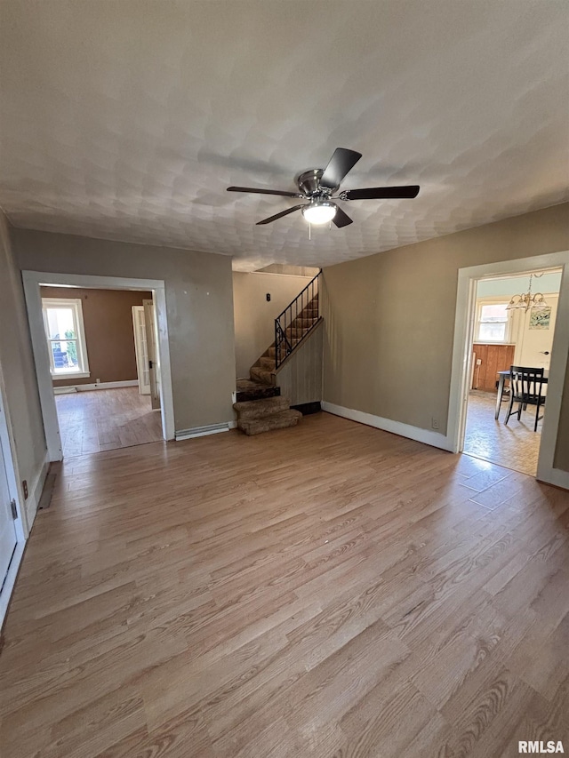 324 S Cottage St, Kewanee, IL 61443 - unfurnished living room with light wood-style flooring, a ceiling fan, stairway, and a chandelier