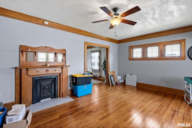 2016 12th St, Rock Island, IL 61201 - living room featuring wood-type flooring, ceiling fan, a fireplace with flush hearth, a textured ceiling, and crown molding