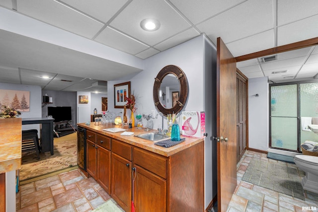 412 24th Ave, East Moline, IL 61244 - kitchen featuring a paneled ceiling, light countertops, light stone finish flooring, brown cabinetry, and black dishwasher