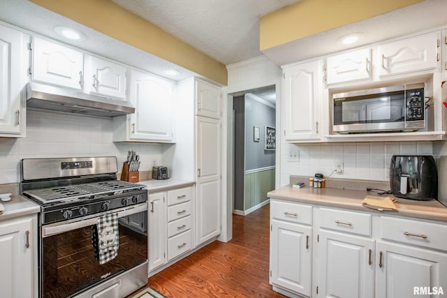 5680 State Route 146 E Highway, Vienna, IL 62995 - kitchen featuring appliances with stainless steel finishes, under cabinet range hood, white cabinetry, light countertops, and wainscoting