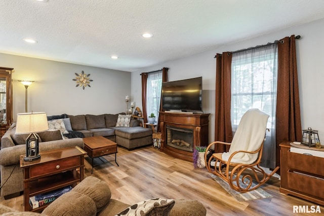 15611 Willow Ct, Sterling, IL 61081 - living area with light wood-style flooring, a textured ceiling, recessed lighting, and a glass covered fireplace
