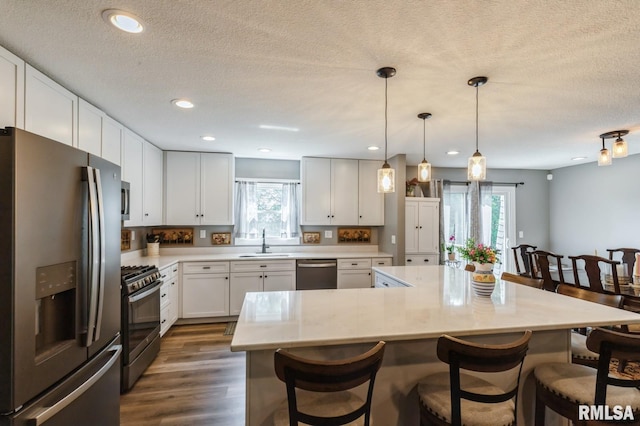 15611 Willow Ct, Sterling, IL 61081 - kitchen featuring appliances with stainless steel finishes, a breakfast bar area, white cabinetry, a textured ceiling, and a center island