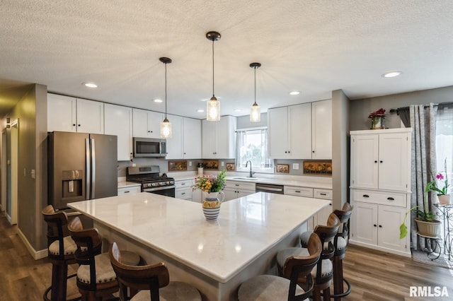 15611 Willow Ct, Sterling, IL 61081 - kitchen with stainless steel appliances, dark wood-style flooring, a kitchen bar, white cabinetry, and recessed lighting
