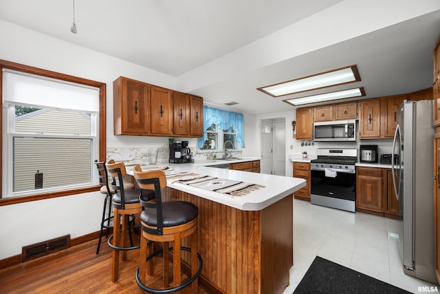 5003 48th St, Moline, IL 61265 - kitchen with stainless steel appliances, a peninsula, light countertops, and brown cabinetry
