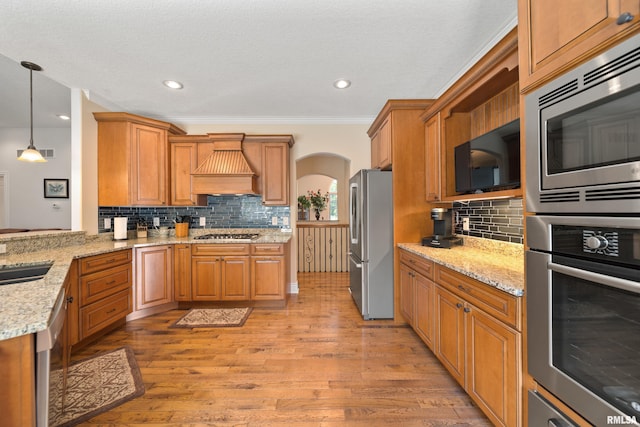 627 10th Ave, Silvis, IL 61282 - kitchen with stainless steel appliances, custom range hood, arched walkways, ornamental molding, and decorative backsplash