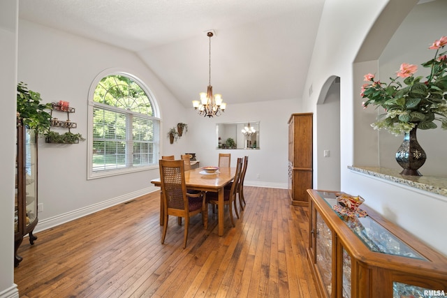 627 10th Ave, Silvis, IL 61282 - dining space with arched walkways, wood-type flooring, a chandelier, and vaulted ceiling