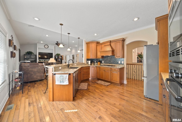 627 10th Ave, Silvis, IL 61282 - kitchen featuring stainless steel appliances, open floor plan, arched walkways, custom range hood, and light wood-type flooring