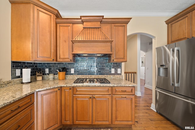 627 10th Ave, Silvis, IL 61282 - kitchen with appliances with stainless steel finishes, wood finished floors, tasteful backsplash, custom range hood, and brown cabinetry